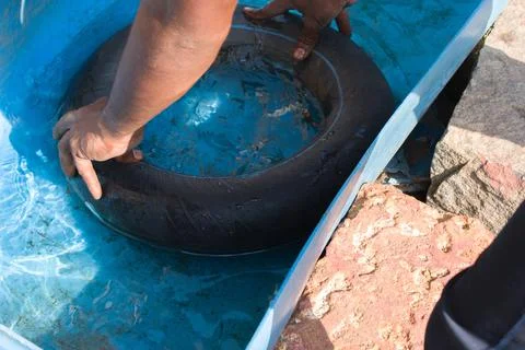 Man testing punctured hole in the tyre tube by dipping the tube in water. Stock Photos
