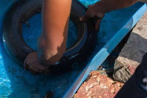 Man testing punctured hole in the tyre tube by dipping the tube in water. Stock Photos