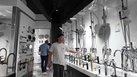 Man Testing Shower Fixtures in Modern Bathroom Showroom Interior, China Video stock 336088614