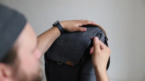 Man testing the weight of a gray backpack and its zipper Stock Footage 144201746
