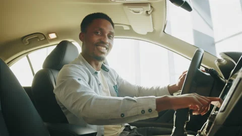 A man tests a new car. Side view of focused african man sitting on driver's seat Stock Footage 174849092