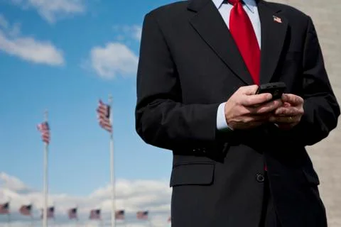 A man text messaging, American flags in the background Stock Photos