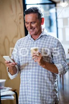 Man Text Messaging On Mobile Phone While Having Coffee