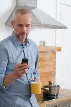 A man text messaging while a pot steams behind him Stock Photos