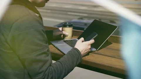 Man texting and drinking coffee to go while working outdoors Vídeo Stock 80965574