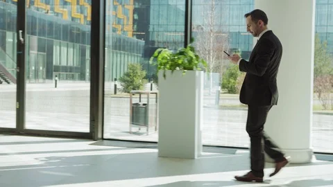 Man texting on cell phone walking in business center Video stock 108679908