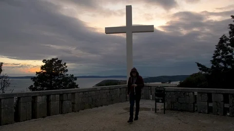 Man Texting in Front of Large White Cross Wearing Hoodie, Walking Towards Camera Stock Footage 90636475