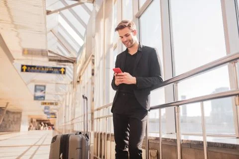 Man texting with his friends while waiting for a flight Stock Photos