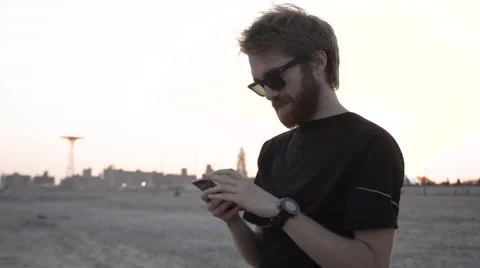 Man texting on his smart phone at the beach Vídeo Stock 63607496