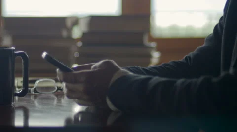 Man texting a message on smart phone while drinking coffee in an office of cafe Stock Footage 65338841