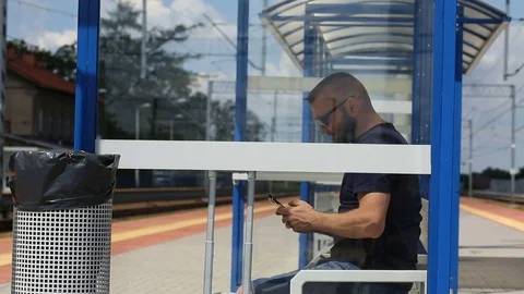 Man texting messages on smartphone while sitting on the train stop Stock Footage 78654743