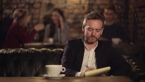 Man texting on notebook and drinking coffee in cafe Video stock 69964156