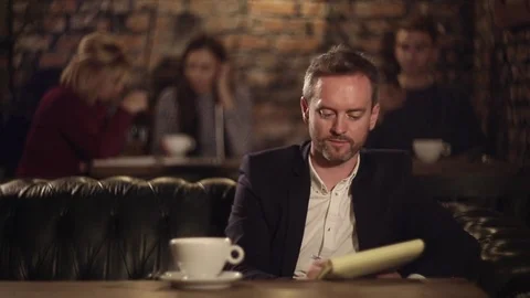 Man texting on notebook and drinking tea in cafe 動画素材 70839917