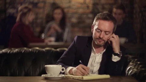 Man texting on notebook and talking on the phone 動画素材 69942613