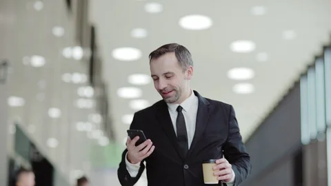 Man texting on phone and drinking coffee in office hall Stock Footage 108681432