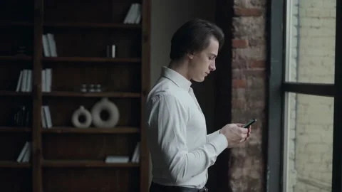 Man texting on the phone next to the window Stock Footage 168648498