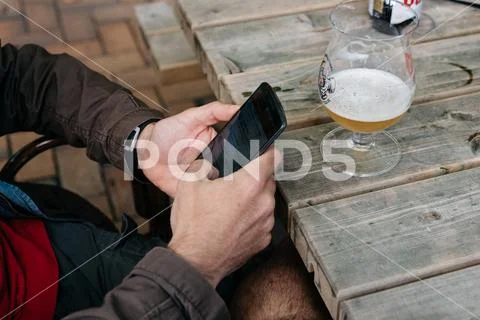 Man texting on phone while drinking beer sitting on a bar Stock Photos