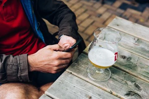 Man texting on phone while drinking beer sitting on a bar Stock Photos