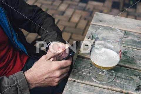 Man texting on phone while drinking beer sitting on a bar Stock Photos