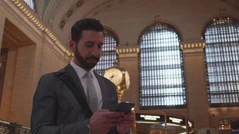 Man texting on phone while waiting at central station during busy hours Stock Footage 312684869