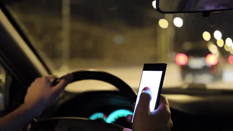 Man texting with a smartphone and driving car at night Stock Footage 104704551