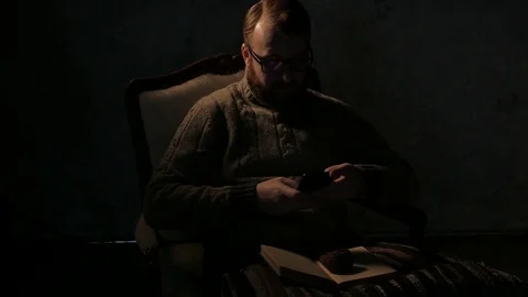 Man texting with a smartphone in a dark room and smoking pipe. 4K UHD Stock Footage 73363084