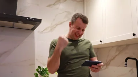 Man Texting on Smartphone in Modern Kitchen During Evening Stock Footage 273533369