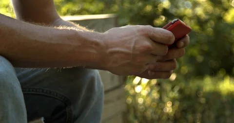 Man texting on a smartphone in the park on a sunny day. 4k 60 fps Stock Footage 111687203