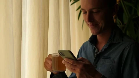 Man Texting on the Smartphone while Drinking Tea Stock Footage 137524191
