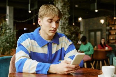 Man Texting on Smartphone While Sitting in Modern Cafe Stock Photos