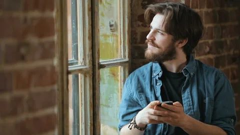 Man Texts Message by Window 動画素材 92695949