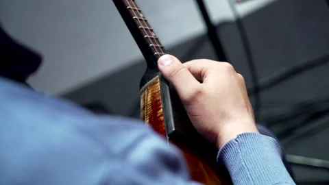 A man from a theater orchestra in a blue jacket holds a balalaika at a rehearsal 스톡 동영상 154870828