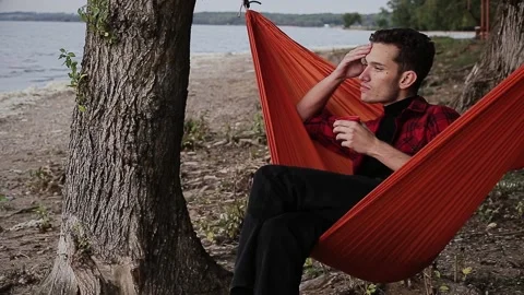 Man with thermos sitting in hammock Stock Footage 168840684
