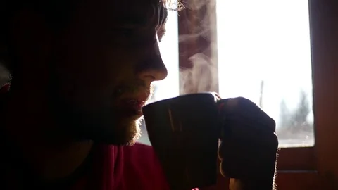 A man with a thick beard and a short sitting opposite the window and drink Stock Footage 73115384