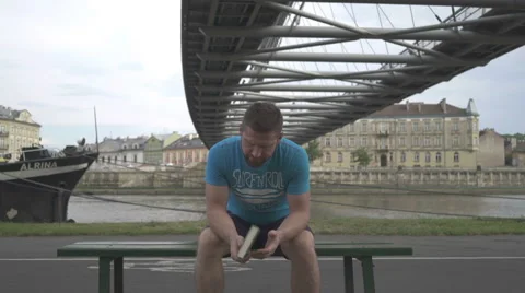 Man is thinkig over, sitting on the bench against the river. Vidéo 65188257