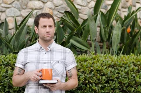 Man thinking about the future holding a book and orange cup outside. Foto stock
