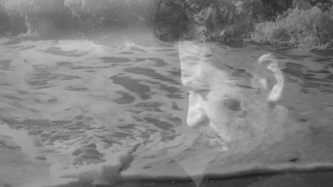 Man thinking in front of the ocean dissolve with sea black and white slow mot Stock Footage 117187015