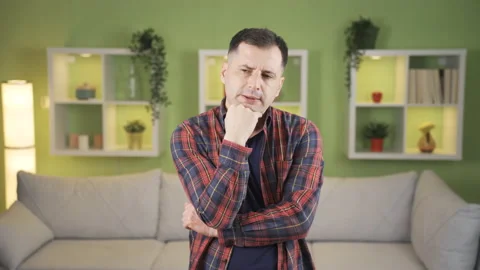 The man is thinking of a serious plan at home, solving the problem in his mind  Stock Footage 235589520