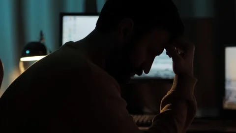 Man Thinking. Silhouette of man working at computer holding his forehead with Stock Footage 306215552