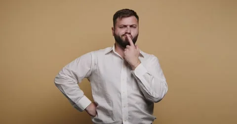 Man thinks deeply while posing with a thoughtful expression against a plain.. Vídeos de archivo 326797860