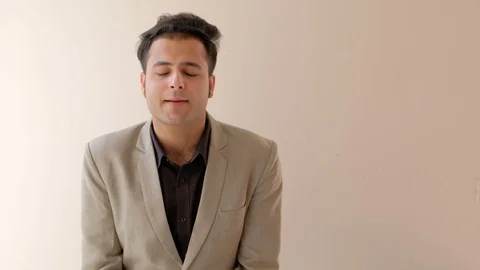 Man thinks, puts his hand on his face and looks at camera  Stock Footage 100529796