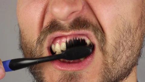 Man thoroughly brushes his teeth with toothbrush, from top to bottom, closeup Stockbeeldmateriaal 94927089