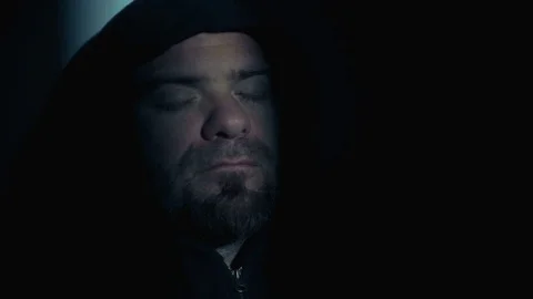 Man with thoughtful hood in the dark opens his eyes and looks at the light Video stock 74715866