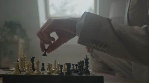 Man thoughtfully playing chess in a cozy, sunlit room on a winter day Stock Footage 319957311
