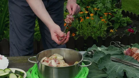 Man threading meat on skewer over marinade pot outdoors, barbecue prep Video stock 329232514