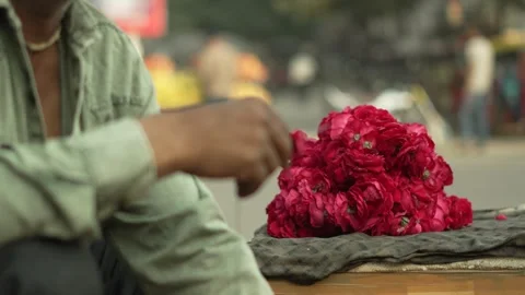 Man Threading Red Rose Petals into Flower Garland at Market Stall Stock Footage 320363001