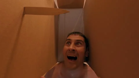 A man is threatened with a sharp knife, piercing the box containing his head. Stock Footage 317177158