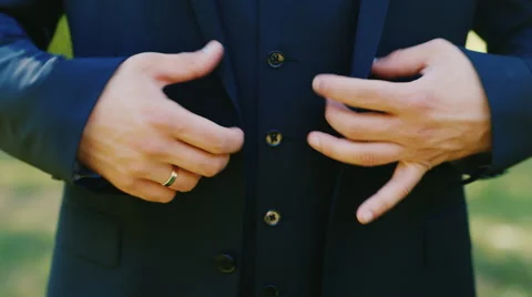 A man in a three-piece suit buttoning outdoors Stock Footage 61990054