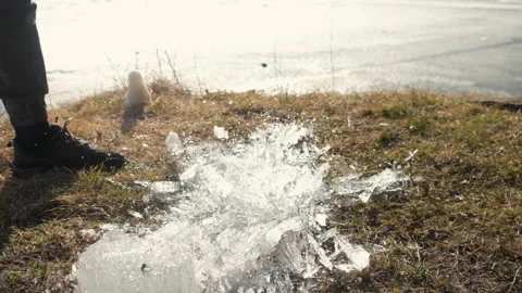 Man throw close-up ice block breaks near frozen river on nature in sunny day. Stock Footage 311865737