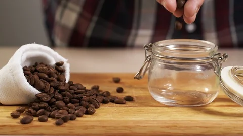 Man throw roasted coffee bean from hand into jar closeup with white bag near 4K Stock Footage 113055891